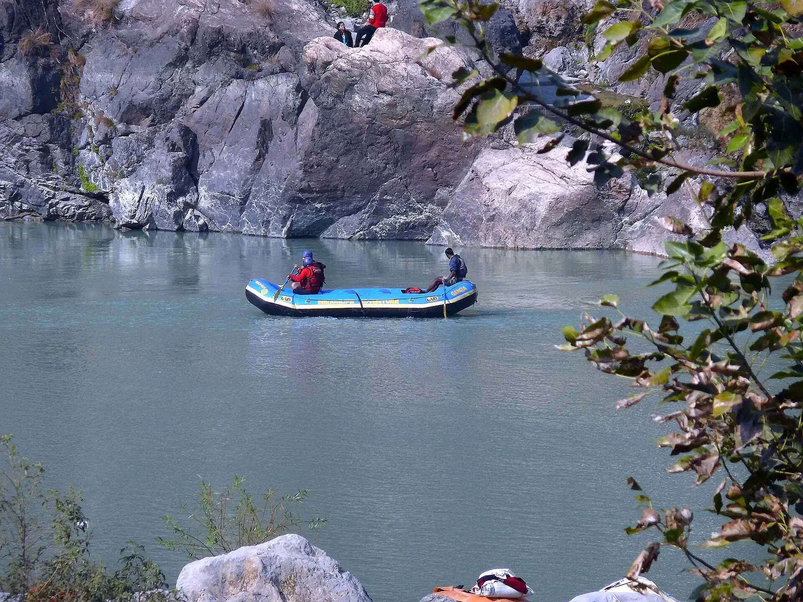 A raft on the green Ganga below rocky cliffs at Rishikesh