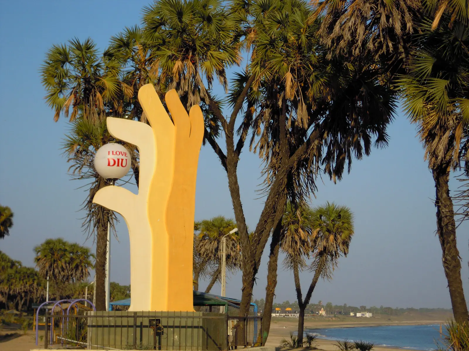 The palm-fringed crescent of Nagoa Beach, Diu, with its landmark hand-shaped sculpture