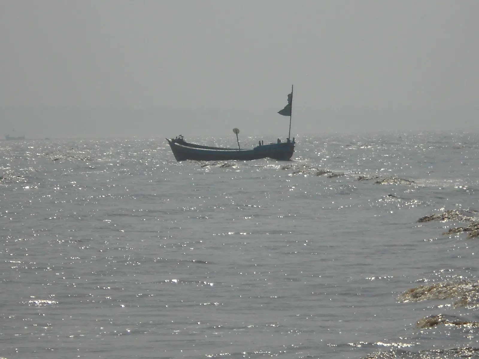 A local fishing boat anchored offshore at Jampore Beach, Daman