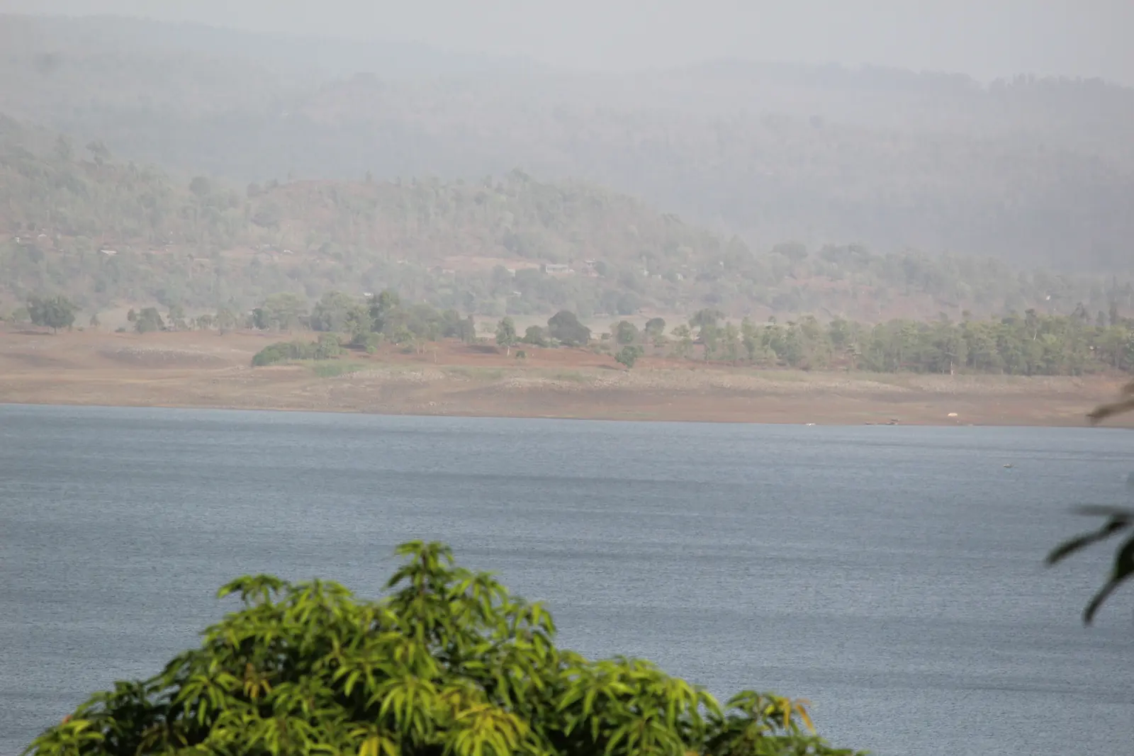 The wide Madhuban Dam reservoir on the Damanganga river near Silvassa, framed by forested hills