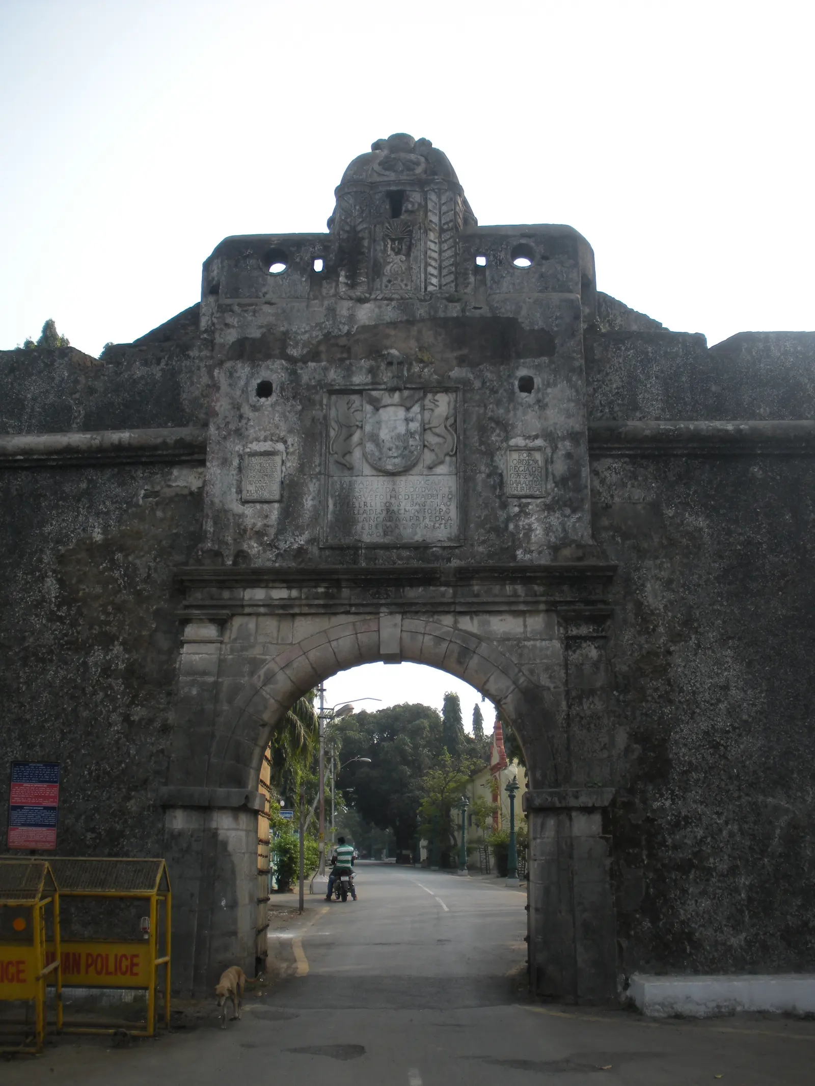 The weathered stone archway gate of Moti Daman Fort with its carved Portuguese crest