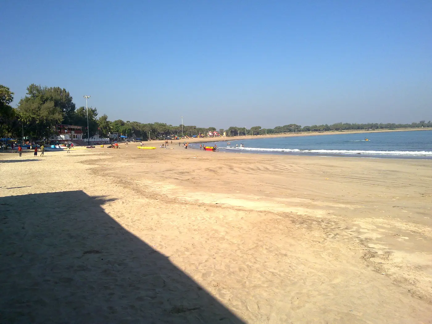Colourful inflatable water sports equipment and beachgoers along the sandy shoreline at Nagoa Beach, Diu