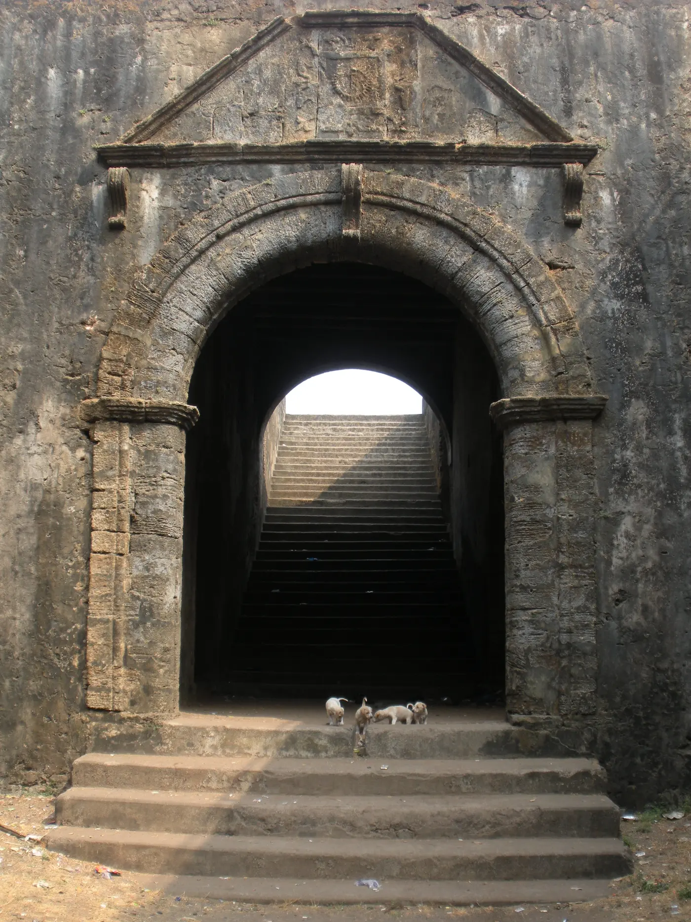 A weathered stone archway and stairway inside Nani Daman Fort (Fort of St. Jerome)