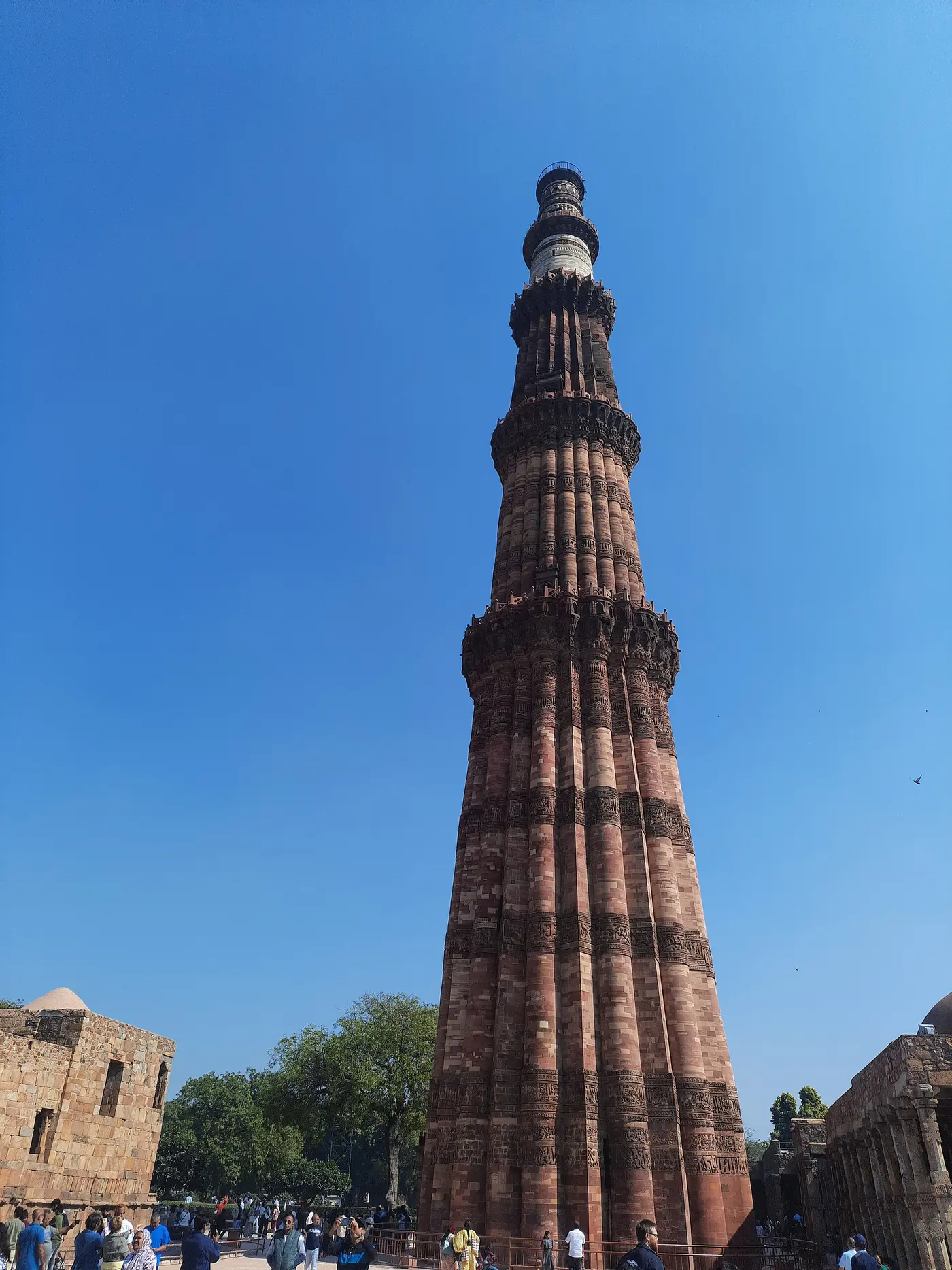 The tapering red sandstone and marble tower of Qutub Minar rising against a clear blue sky