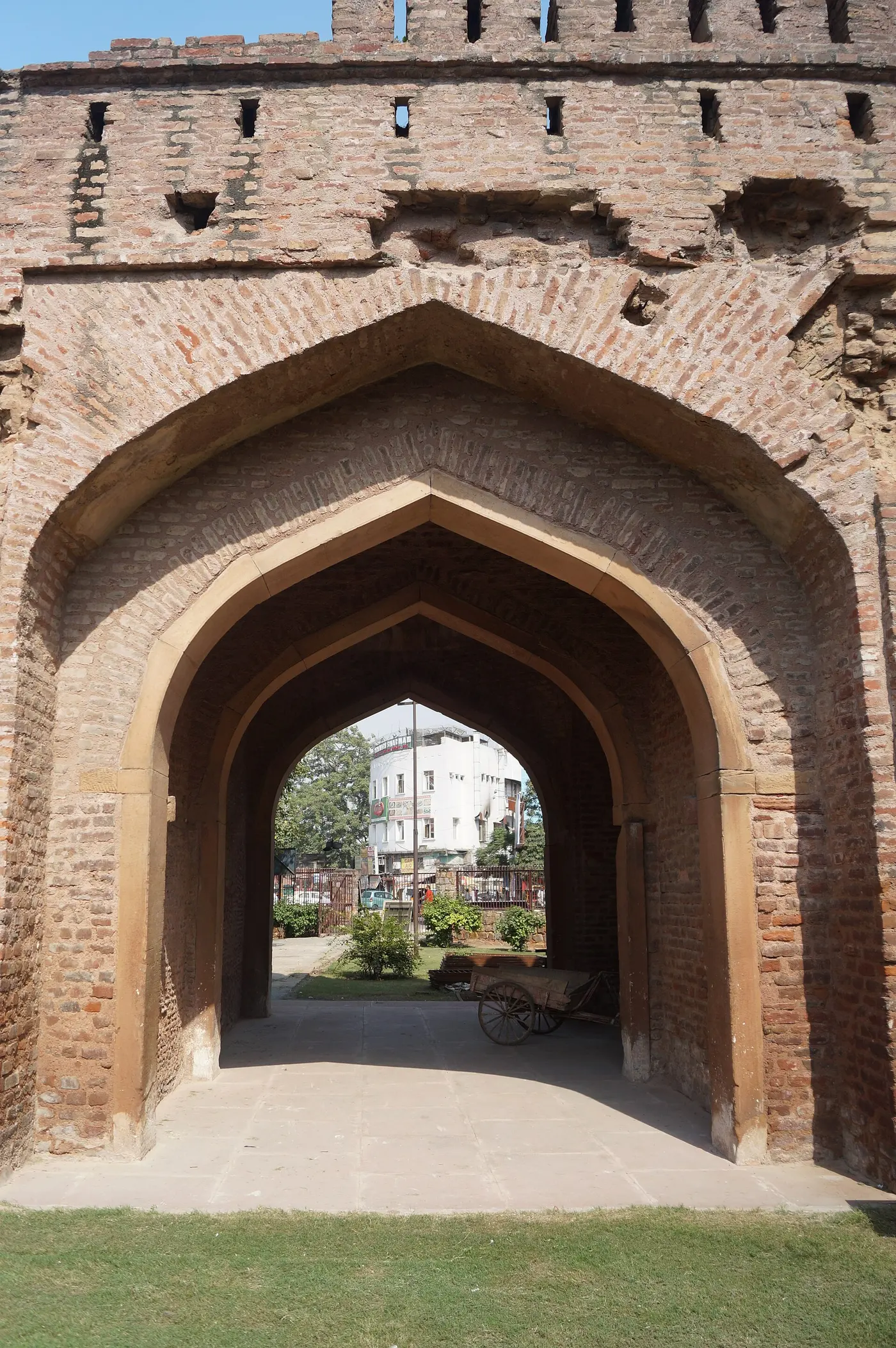 The twin-arched sandstone and brick facade of Kashmere Gate, rebuilt around 1835, seen from the traffic island