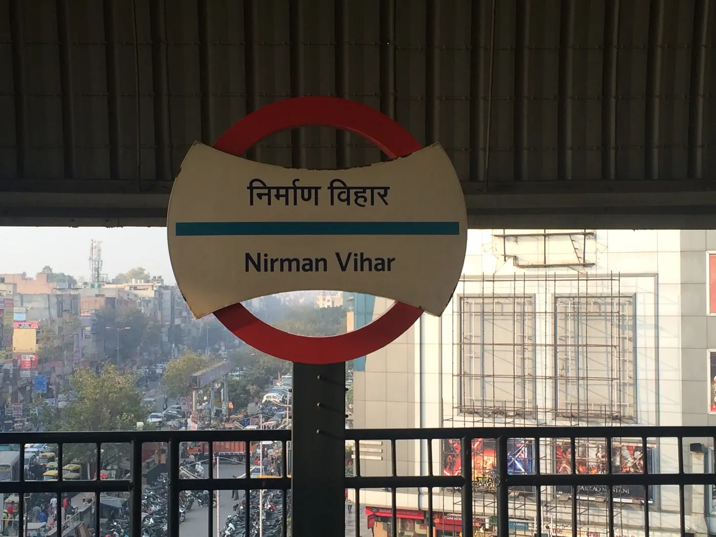 Nirman Vihar Metro Station signboard on the Blue Line, overlooking the dense market below