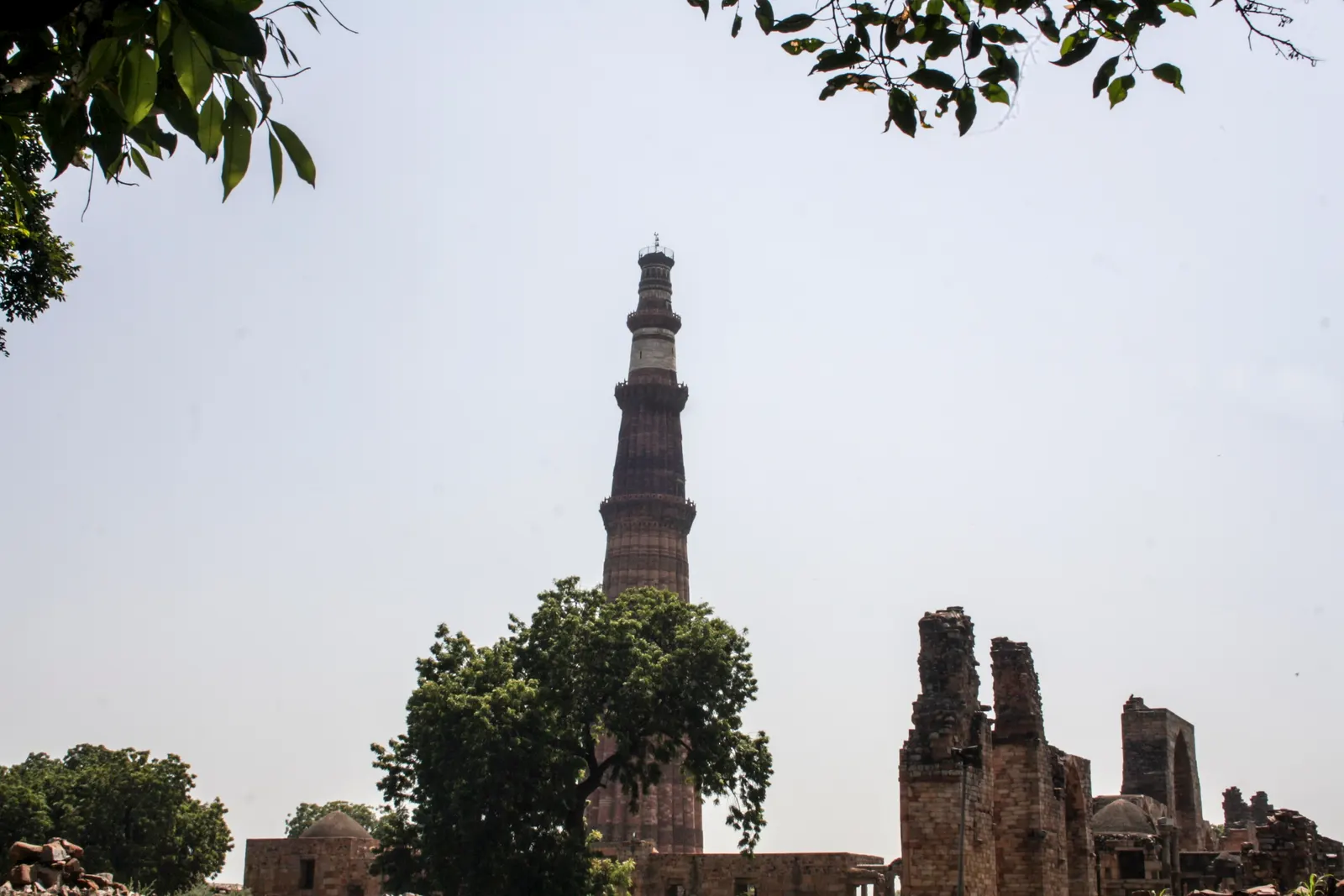 The Qutub Minar tower rising above the lawns of Mehrauli Archaeological Park, Delhi