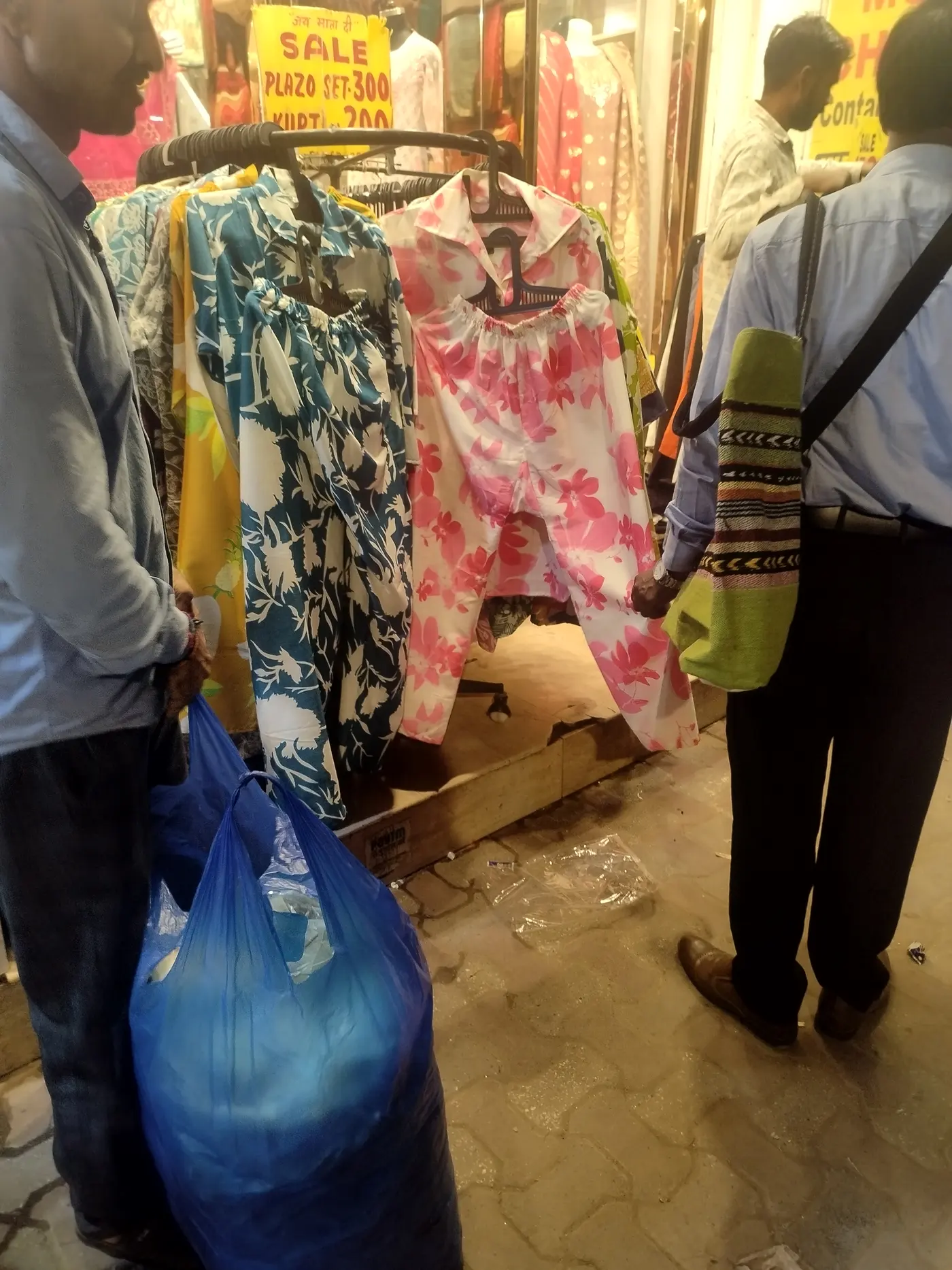 Shoppers examining discounted plazo sets and kurtis hung at a sale stall in Sarojini Nagar Market