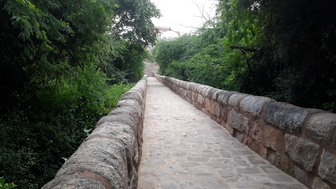 The sand-coloured fortified mausoleum of Ghiyasuddin Tughlaq with its sloping walls, across the road from Tughlaqabad Fort