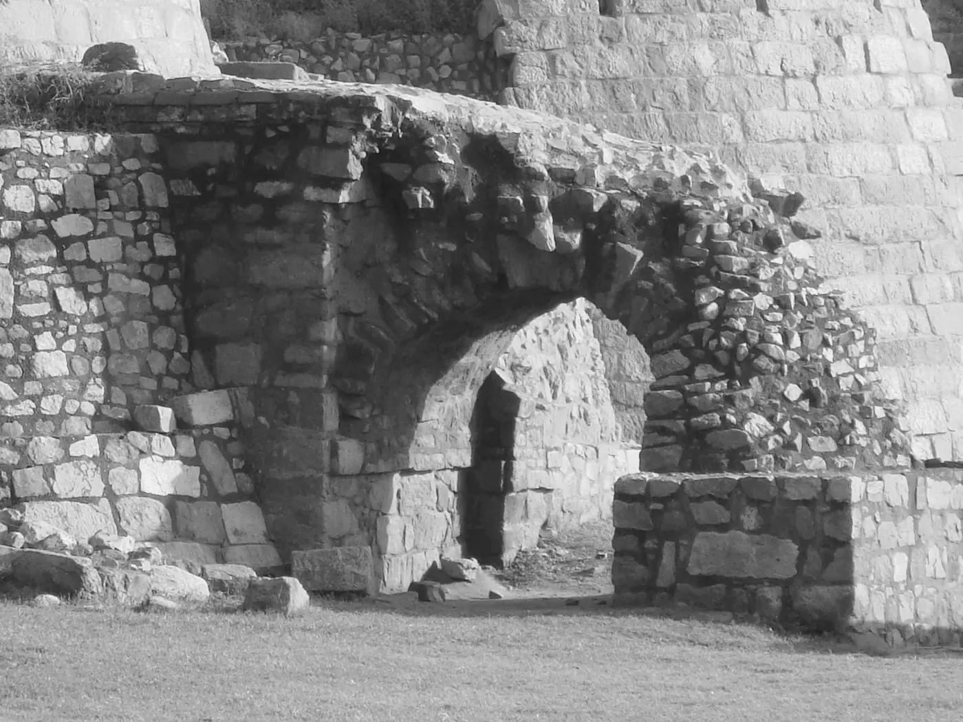 Ruined citadel walls and collapsed stone structures inside Tughlaqabad Fort's inner complex