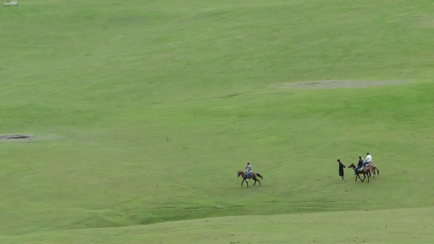 Pony riders crossing the wide green meadow at Doodhpathri, Kashmir