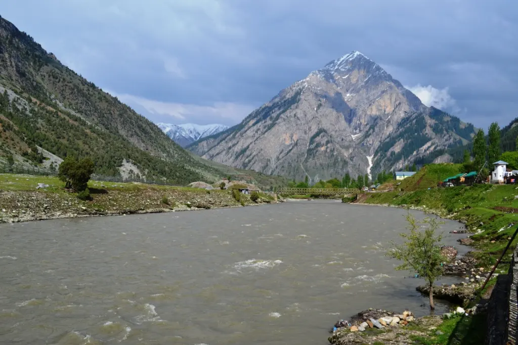 A close, cloudy-sky view of the snow-streaked Habba Khatoon Peak rising above the Kishanganga River