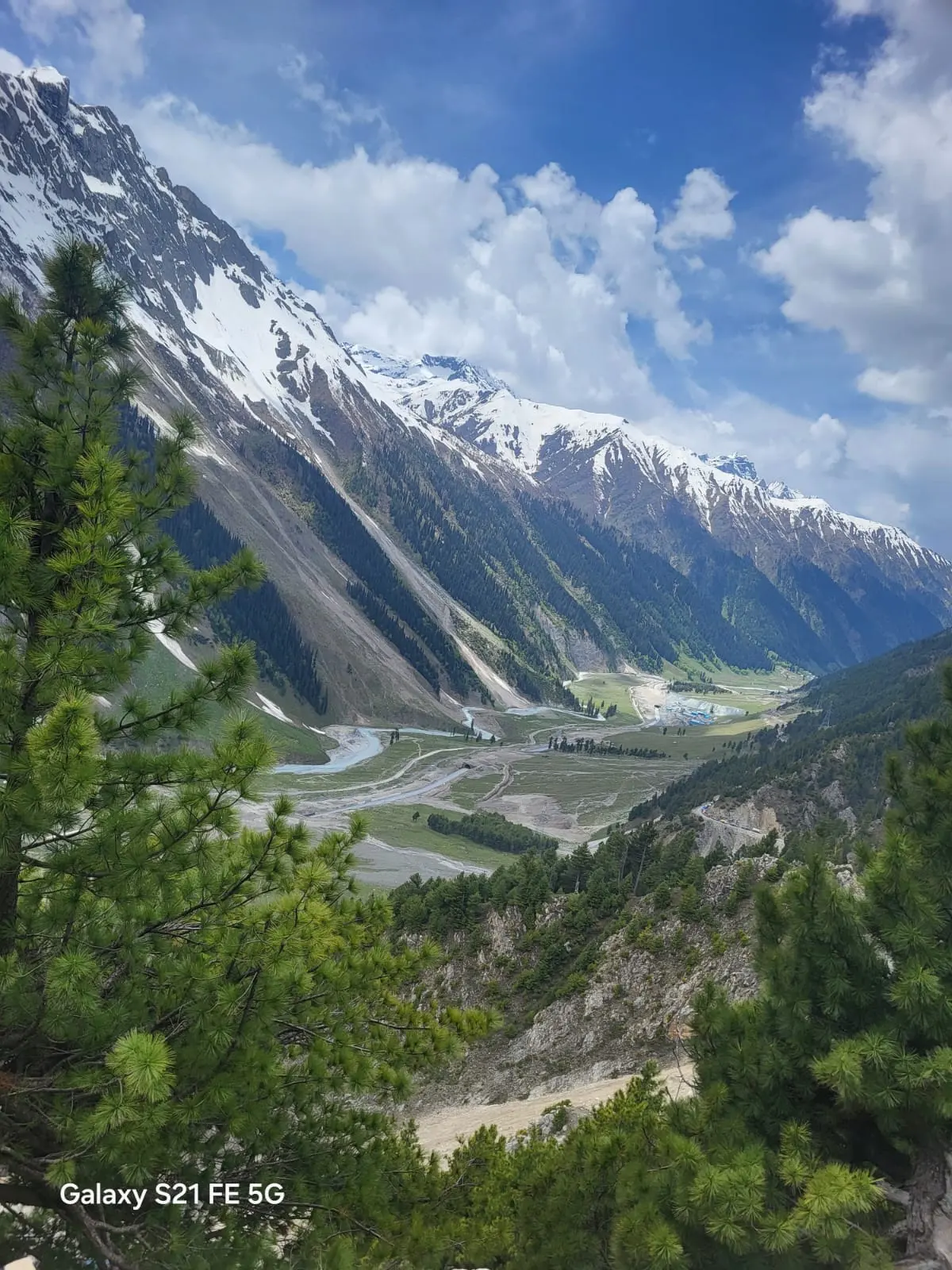 The Sindh valley and switchback road seen from the climb toward Zoji La pass, with snow-capped peaks behind