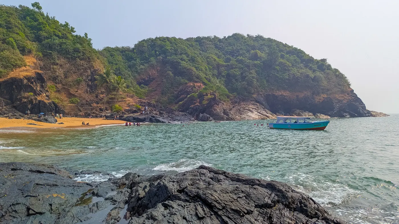 A boat anchored off Paradise Beach's secluded cove near Gokarna, framed by forested headlands
