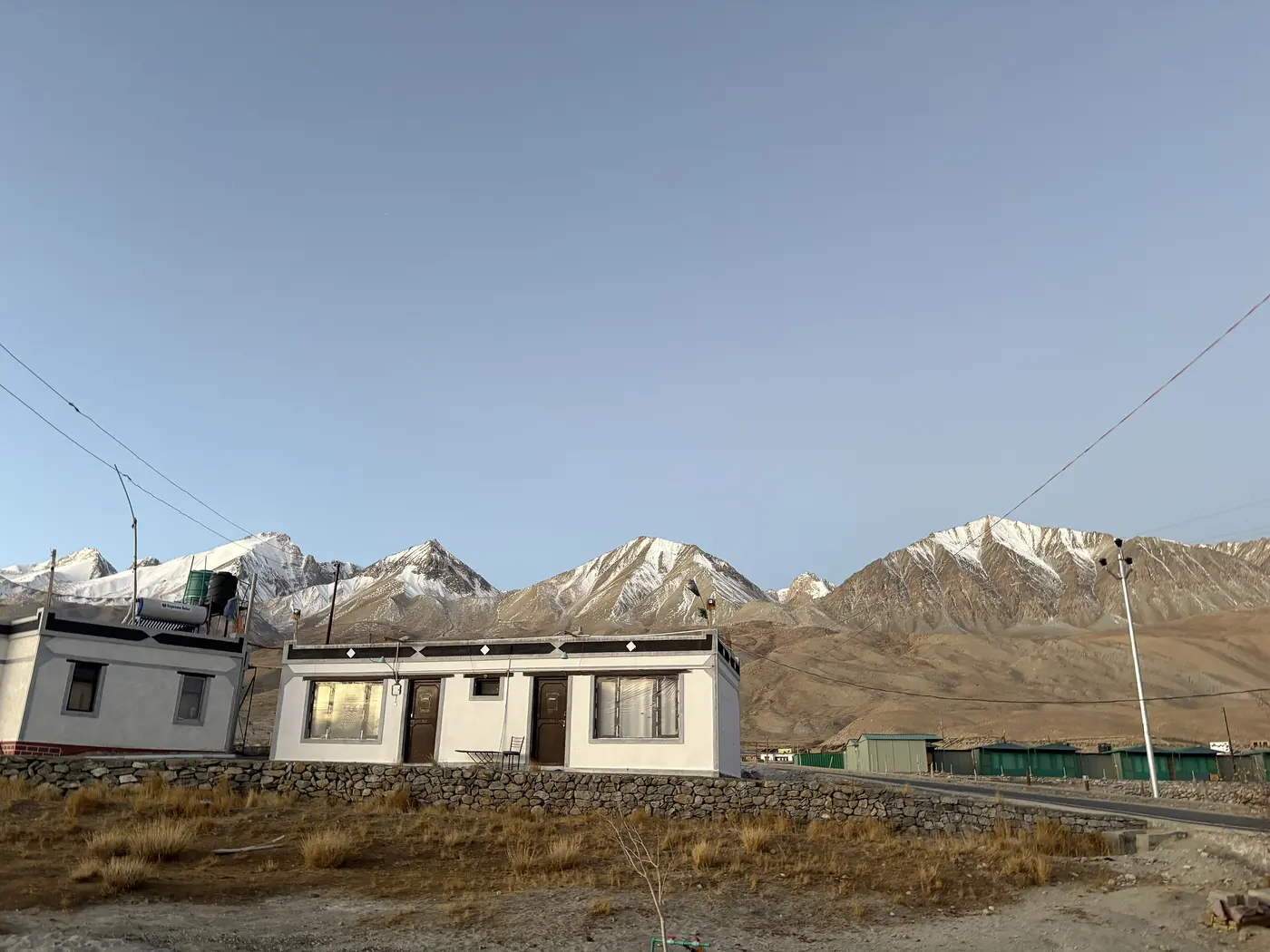 A homestay building in Hanle village at dusk, snow-capped Changthang peaks behind