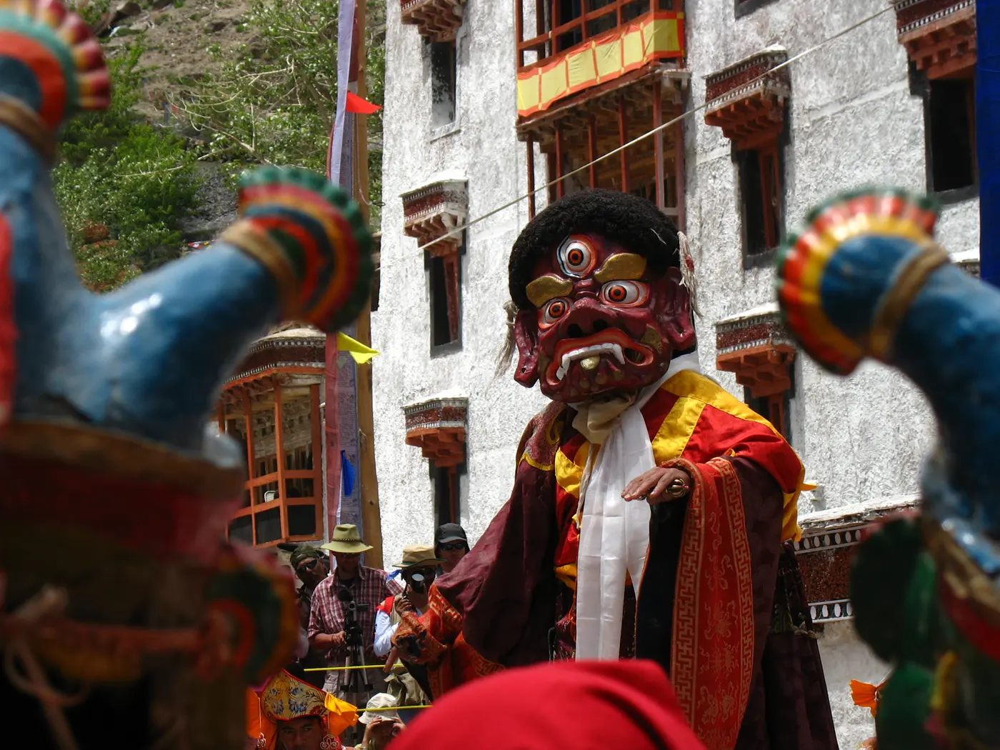 A monk in an elaborate red wrathful-deity mask and brocade robes performing the cham dance at the Hemis Festival