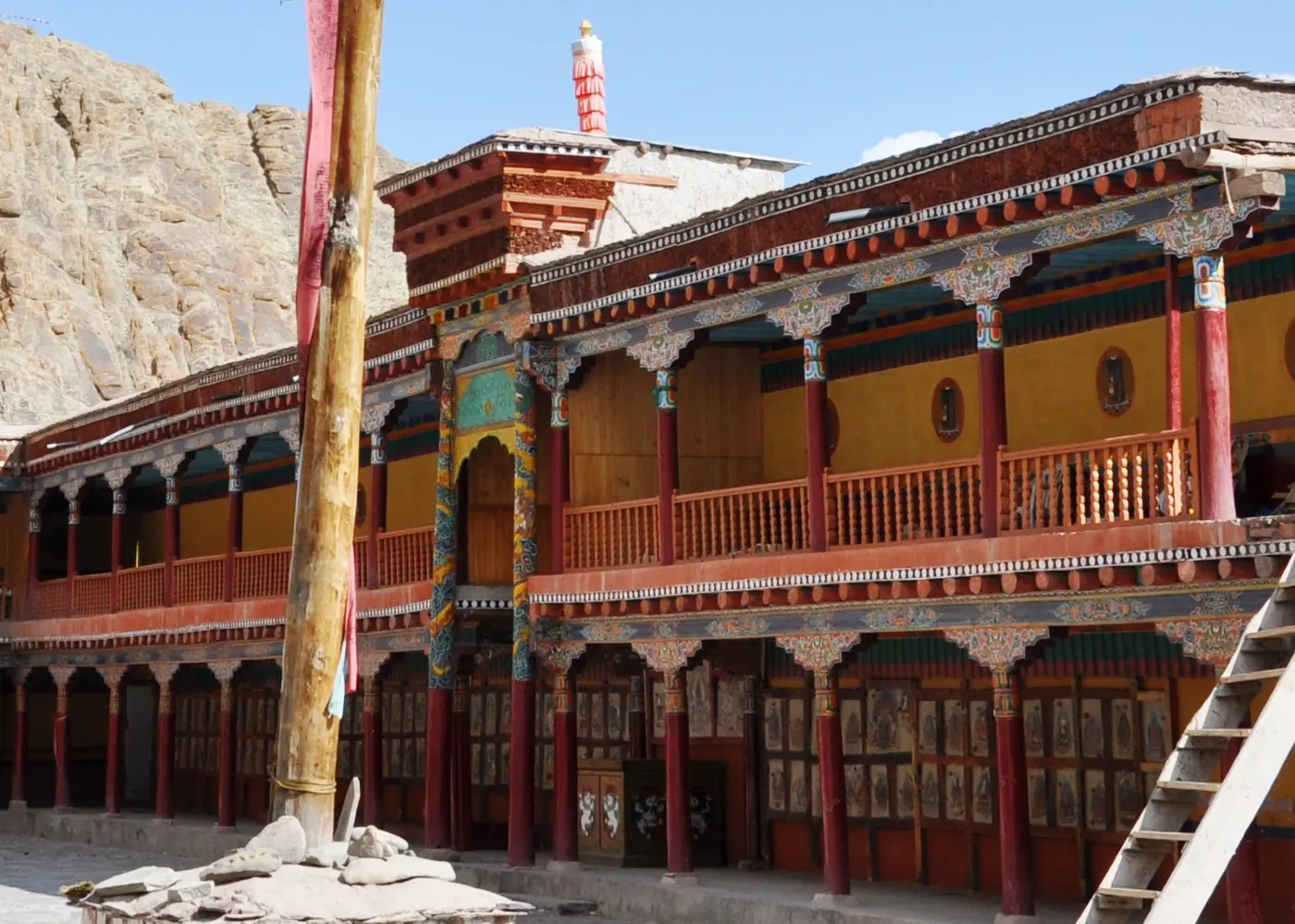 The colonnaded courtyard of Hemis Monastery with painted red pillars and thangka-lined walls