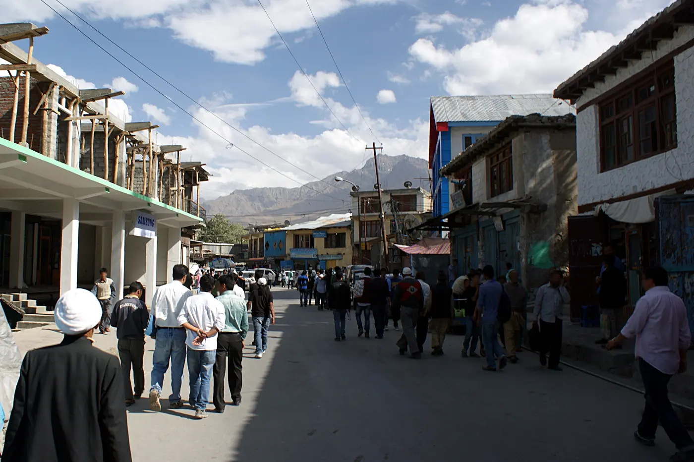 Kargil's main bazaar street lined with traditional wooden-balconied shopfronts and mountains behind