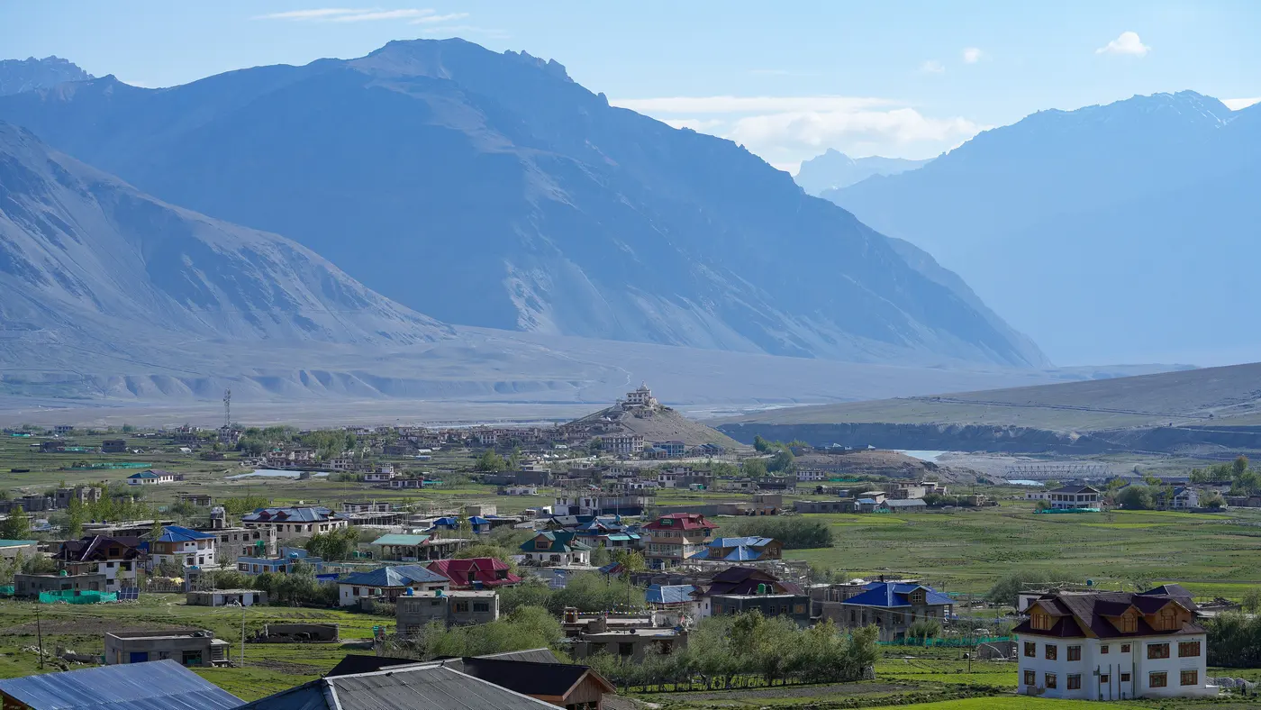 Padum town spread across the valley floor with the ruined Pipiting fort and gompa on its hillock, Zanskar mountains behind