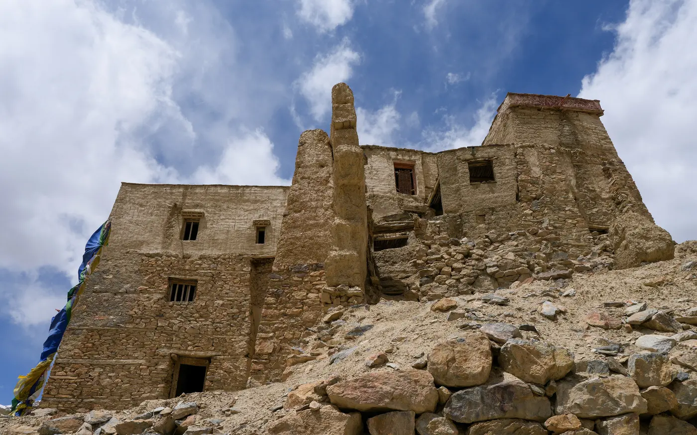 The mud-brick ruins of Zangla's royal palace (Zangla Khar) against a blue Zanskar sky, hung with prayer flags