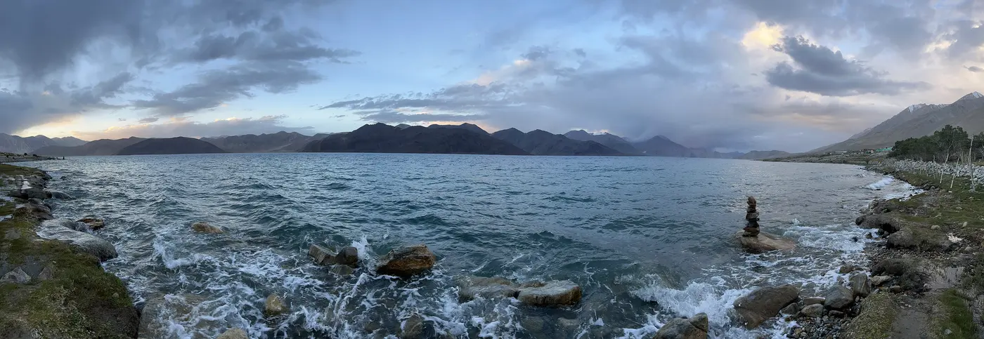 The quieter south shore of Pangong Tso near Spangmik, with rocky shoreline and mountains across the water