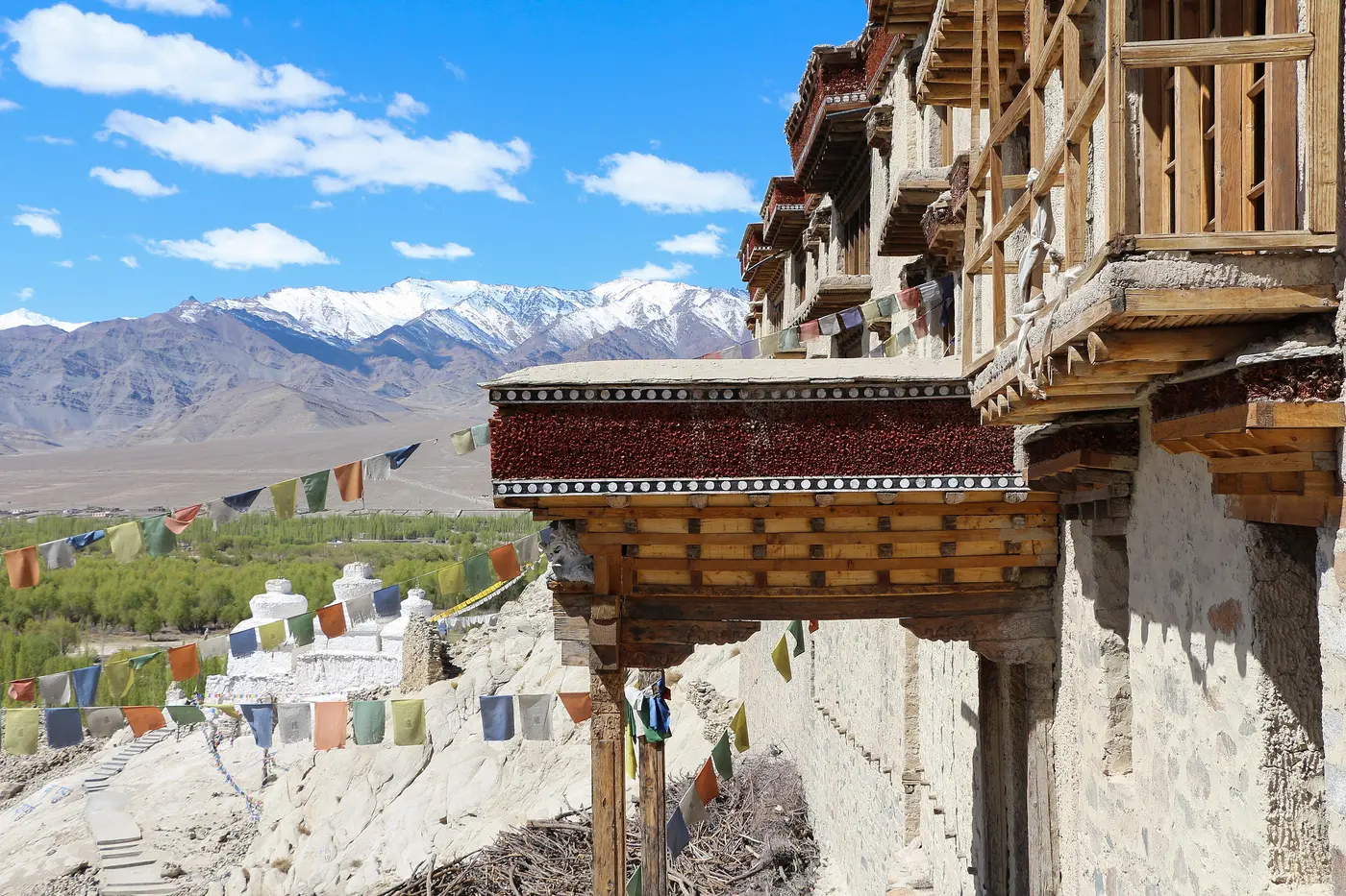 Shey Palace's whitewashed eaves strung with prayer flags, with whitewashed stupas and snow-capped mountains behind