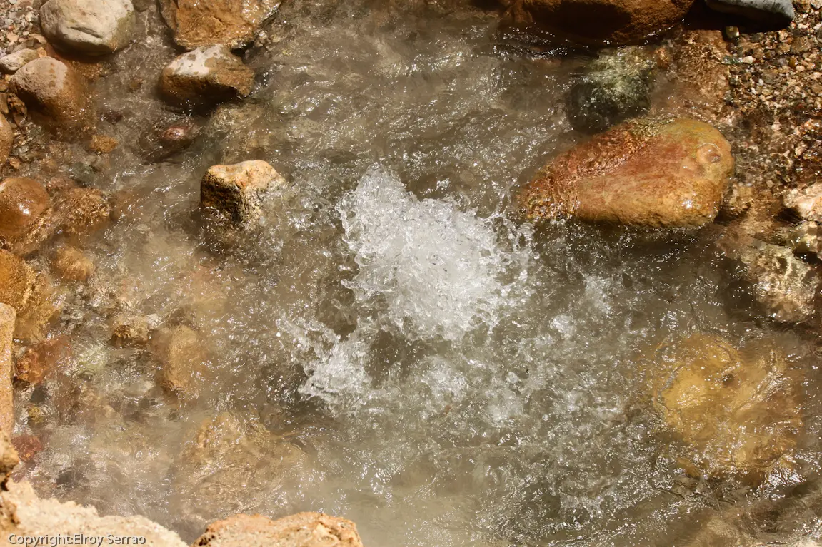 Steaming natural hot spring water bubbling up among riverbank rocks at Chumathang, en route to Tso Moriri