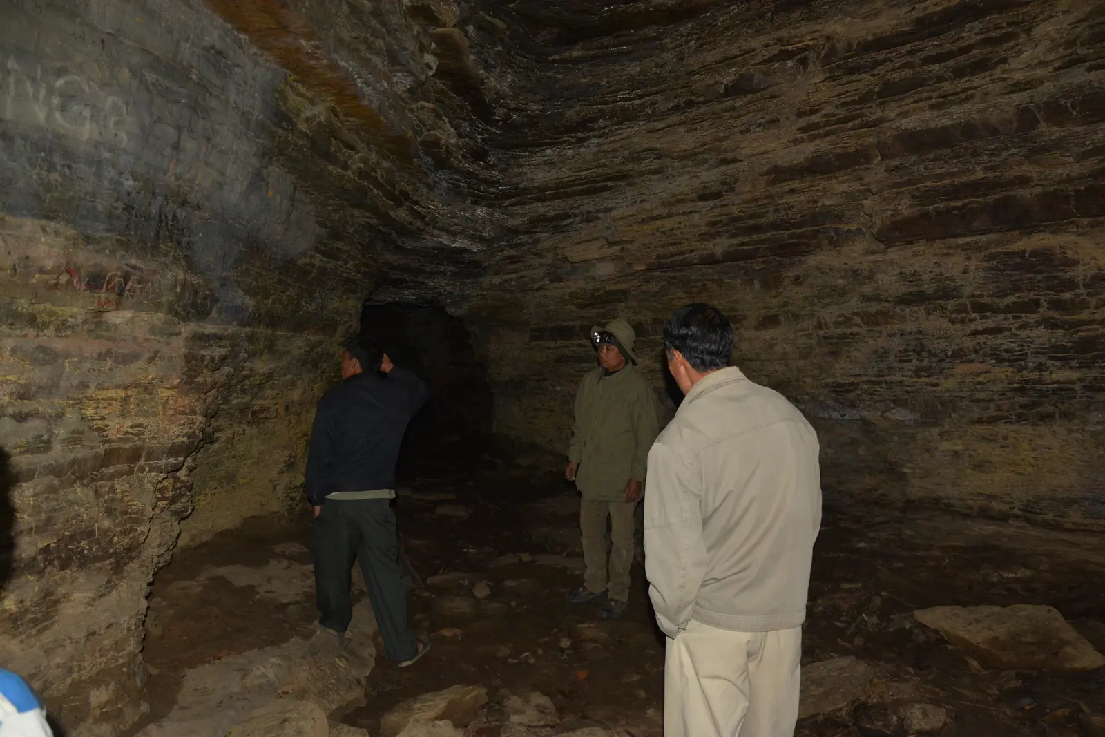 Visitors exploring the layered limestone interior of Tharon Cave, Manipur