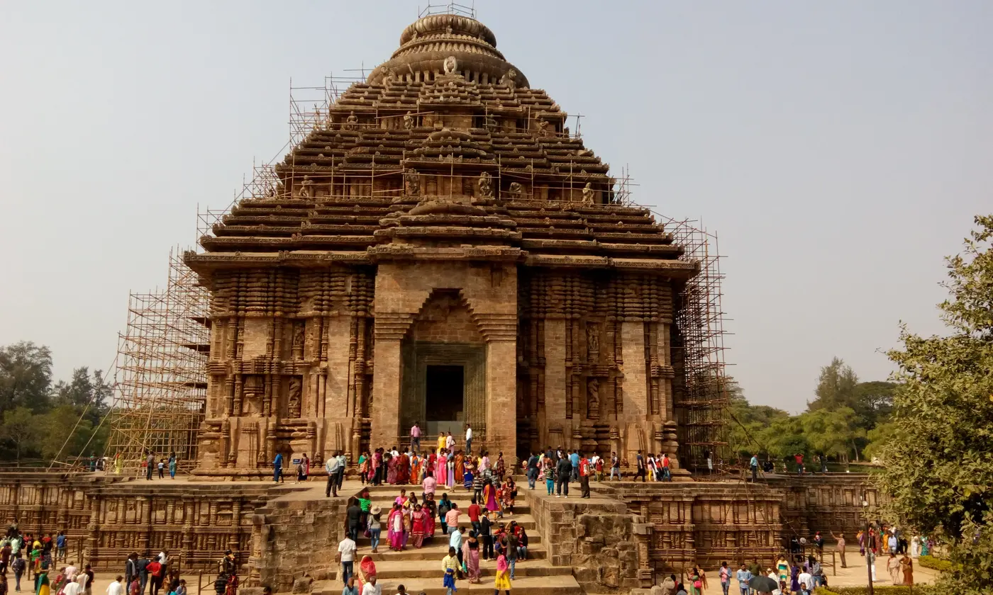 Visitors gathered before the ornately carved stone facade of the Konark Sun Temple