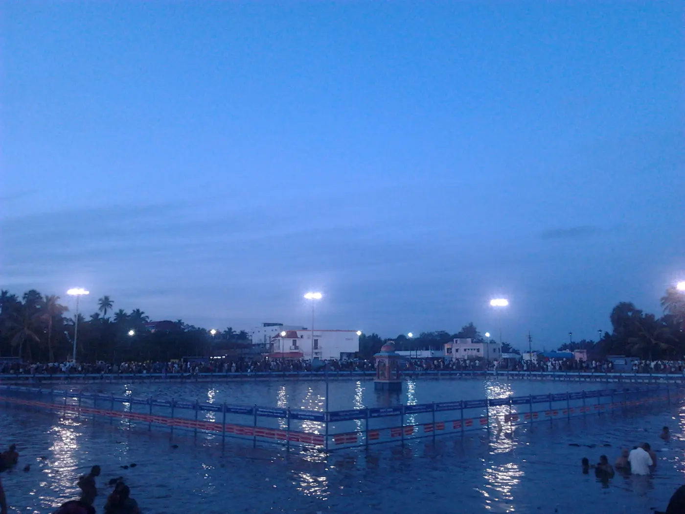 Pilgrims bathing in the Nala Theertham tank at dawn beside Tirunallar's Saneeswaran Temple