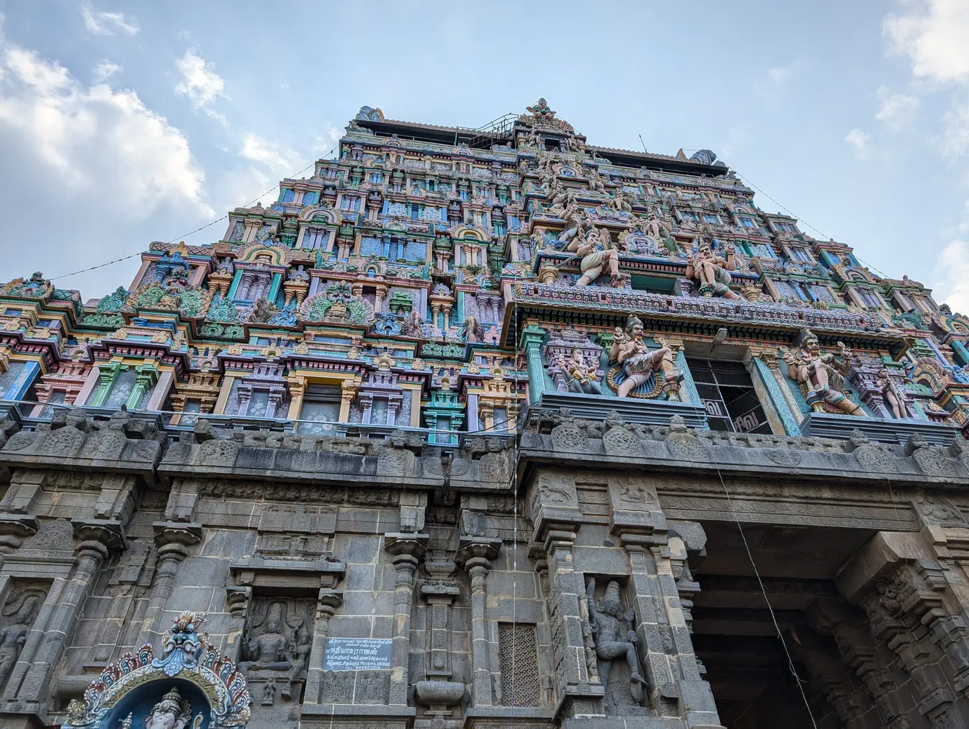 Ground-level view of the sculpted gopuram tower and stone base of the Thillai Nataraja Temple complex, Chidambaram