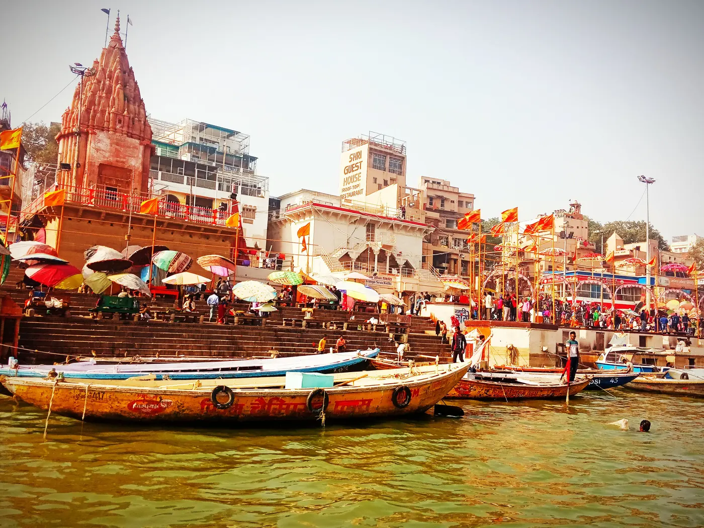 Pilgrims and boats crowding the stone steps of Dashashwamedh Ghat in Varanasi by day