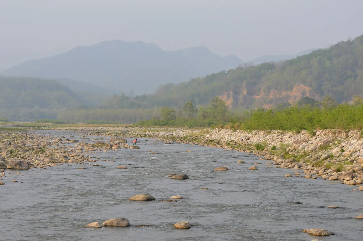 The rocky bed of the Kosi River near Ramnagar, backed by forested hills, along the stretch lined with resorts